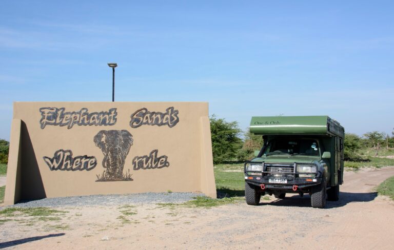 Tafel mit Elefantenbild und „Elephant Sands“, Jeep im Busch in Afrika.