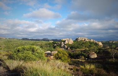 Abgeschiedene afrikanische Savannenlandschaft mit Felsen und Wolken am Himmel.