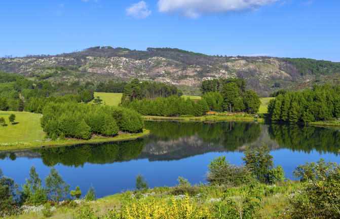 Natursee in Afrika, grüne Landschaft, Berge im Hintergrund, ruhige Natur, afrikanischer Reisetraum.