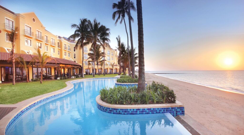 Reichhaltige Parkanlage und Pool direkt am Meer, Sonnenuntergang in Afrika, tropischer Urlaub, Strandurlaub Afrika.