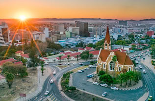 Atemberaublicher Sonnenuntergang über Windhoek, Namibia, mit Stadtskyline und Kirche im Vordergrund.