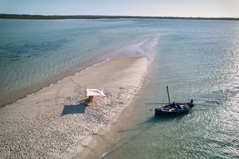 Ein einsamer Strand in Afrika mit Segelboot und Sandbank in kristallklarem Wasser, ideal für Afrikareisen, Safari und Strandurlaub.