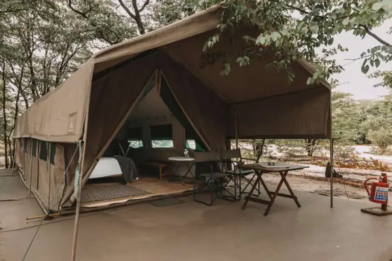 Großes afrikanisches Safari-Zelt mit Lounge-Bereich in der Natur.