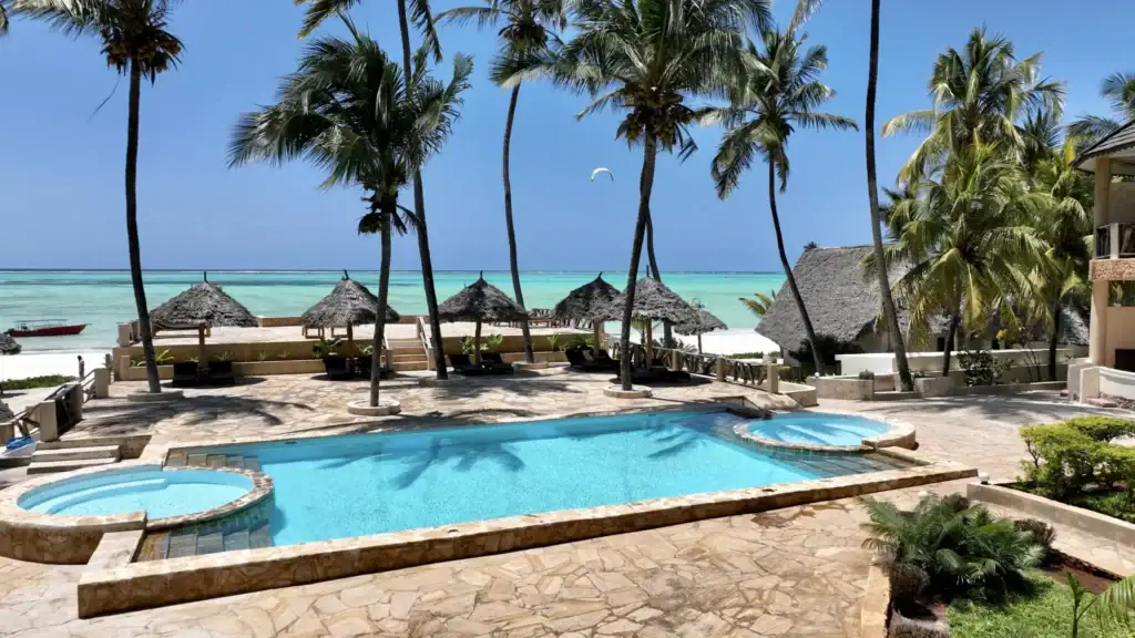 Badezimmer- und Poolbereich mit Meerblick, Palmen und Strandhütten in Afrika, Luxusreise.
