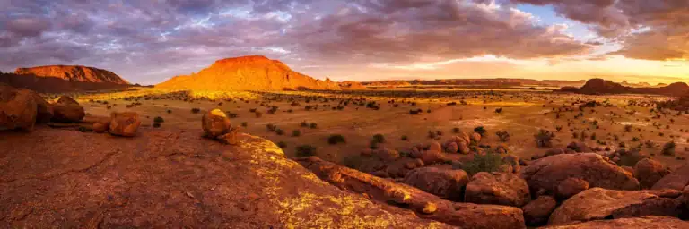 Sonnenuntergang über der namibischen Wüste mit roten Felsen und weiten Ebenen, ideal für Namibia Run.