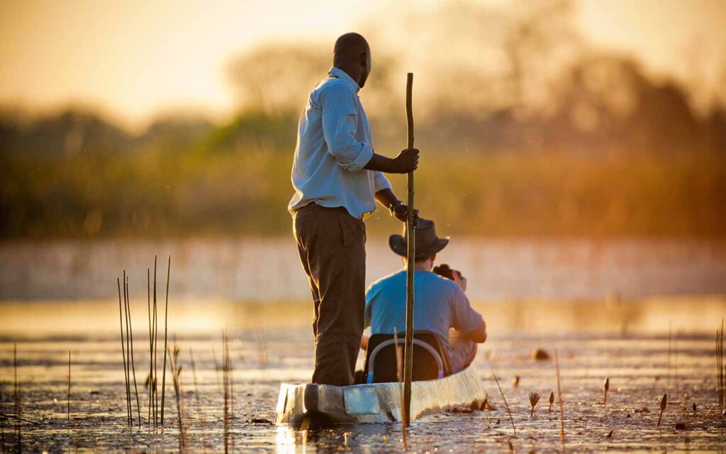Zwei Safari-Gäste auf Bootstour in Botswana, Tierbeobachtung im Wasser.
