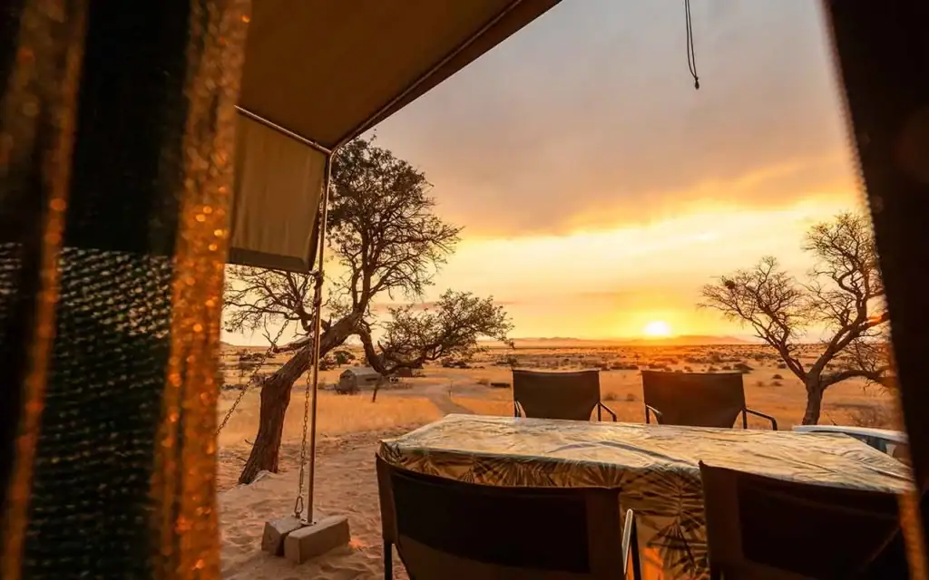 Zeltcamp in Namibia mit Blick auf die afrikanische Savanne bei Sonnenuntergang.