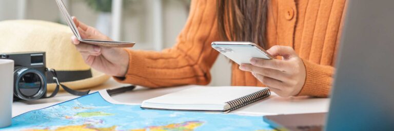 Frau nutzt Smartphone und Tablet für Reiseplanung nach Afrika.