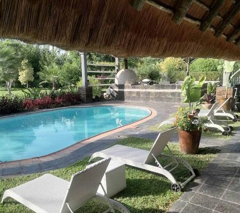 Entspannter Poolbereich mit Liegestühlen und Garten in Afrika.