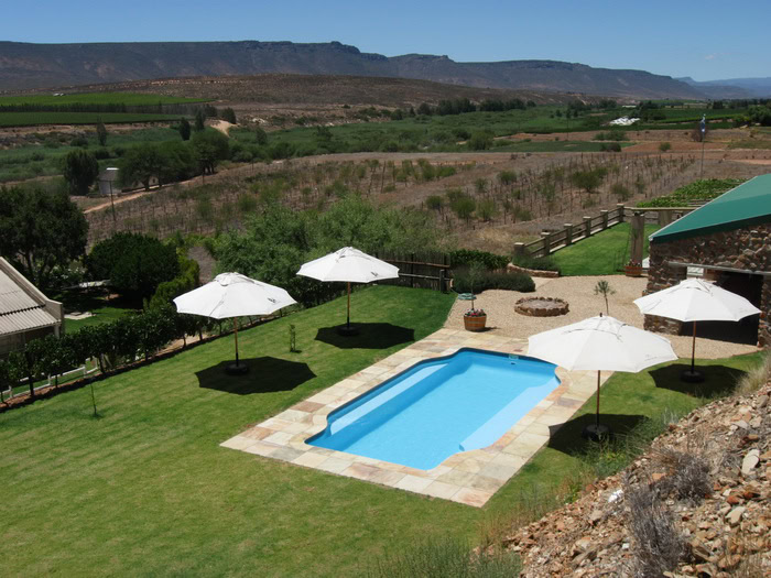 Schwimmbad mit Sonnenschirmen in afrikanischer Landschaft.