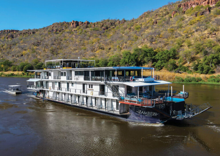 Simbabwes Zambezi Trader Hausboot auf Fluss mit Landschaft im Hintergrund.