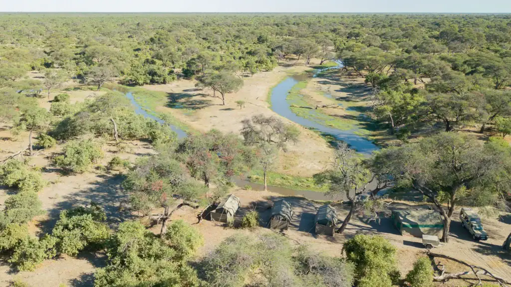Fluss im Mababe Private Reserve mit Bäumen und Safari-Camps.