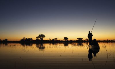Silhouette von zwei Menschen auf einem Boot auf dem Wasser bei Sonnenuntergang.