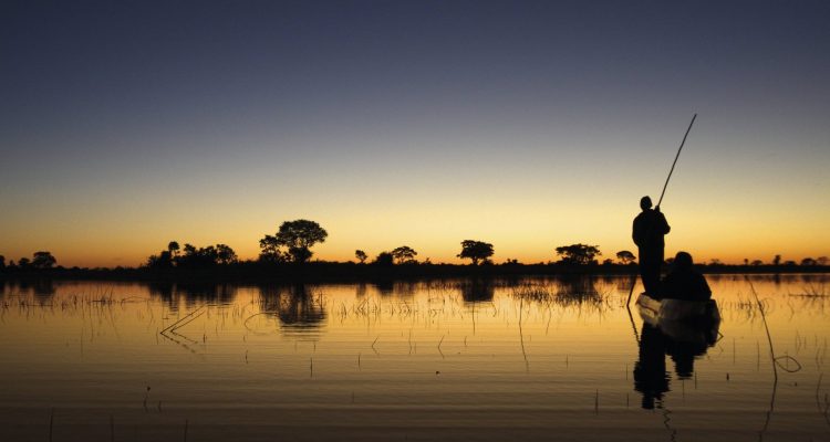Silhouette von zwei Menschen auf einem Boot auf dem Wasser bei Sonnenuntergang.