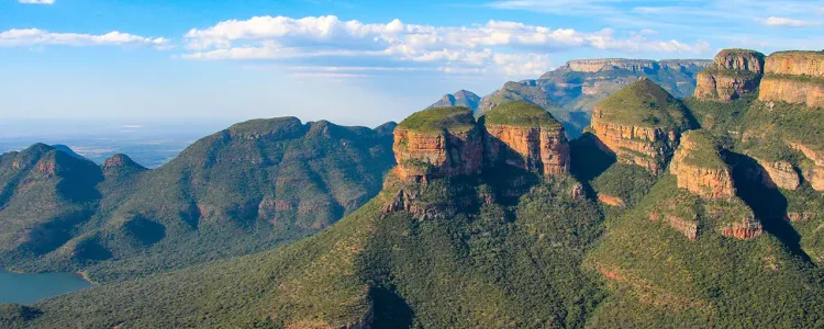 Abstrakte Afrika-Berglandschaft mit grünen Hügeln und Felsen, Blauem Himmel und Wolken.