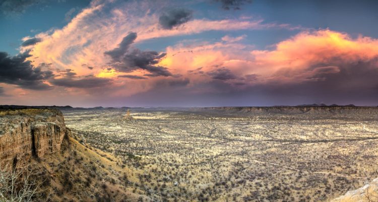 Sonnenuntergang über der afrikanischen Wüste, weite Steppen und Felsen.