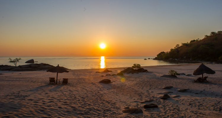 Ein ruhiger afrikanischer Strand mit Sonnenuntergang, Sonne spiegelt sich im Wasser, perfekte Urlaubskulisse.